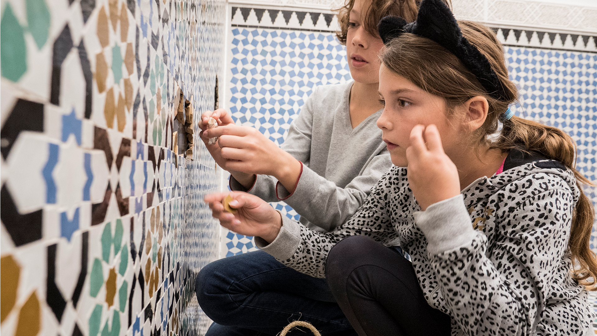 Kinderen in Tropenmuseum spelen met gesneden tegels bij ZieZo muur (tegels gesneden door Laser Chief)